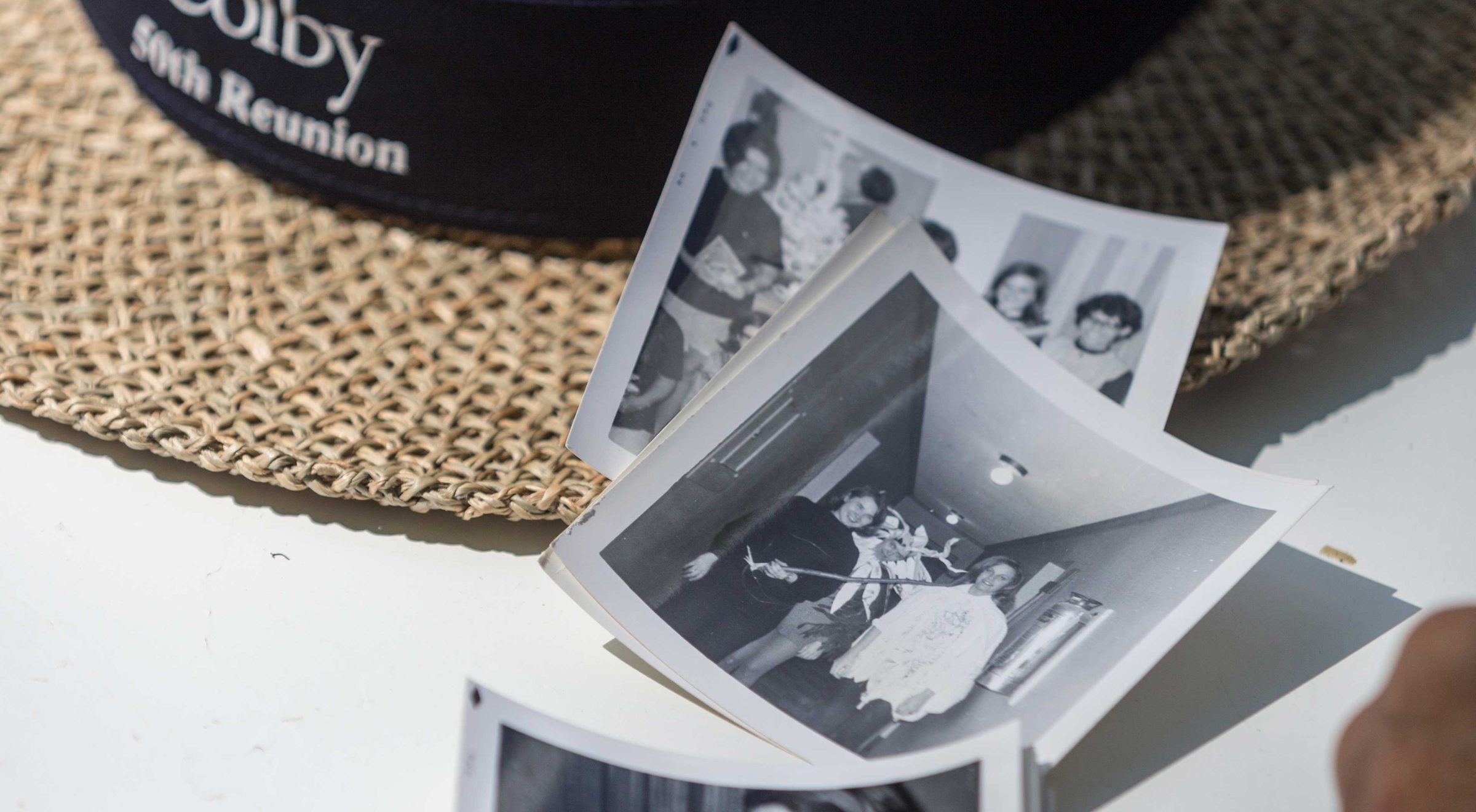 50th Reunion straw hat sits on a table with 3 square black and white photos nearby.